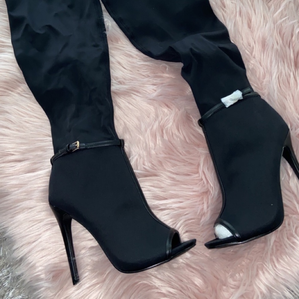 Black knee high, high heeled boots.